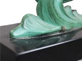 a green sculpture of a wave on top of a black base