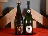 two bottles of wine sitting on a table next to each other