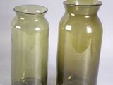two glass vases sitting next to each other on a white surface