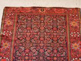 an antique persian rug with red and blue colors on a white floor