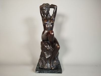 une statue en bronze d'une femme assise sur un rocher