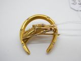une image représentant une broche en or avec une tête de cheval au centre