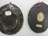 two black plates with gold trims and a label on them