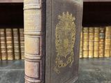 un vieux livre posé sur une table, à côté d'une étagère