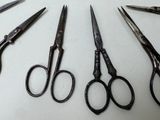 several pairs of scissors are lined up on a white surface