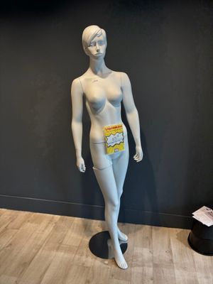 un mannequin dans une pièce, avec un mur noir en arrière-plan