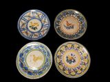 quatre assiettes ornées de motifs d'oiseaux et de fleurs sur fond noir