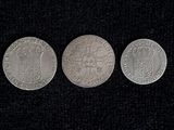 three silver coins sitting side by side on a black surface