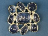 a close up of a broochle with blue stones on a blue surface