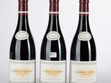 three bottles of red wine sitting next to each other on a table