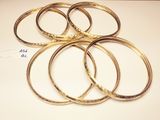 several gold bang bracelets on a white surface with a price tag