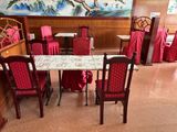 des tables et des chaises recouvertes de nappes rouges dans un restaurant où est accroché un grand tableau au mur