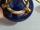 a hand holding a blue glass vase with a gold rim