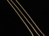a gold plated necklace with a chain on a black background