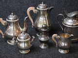 five silver teapots and a coffee pot on a black background