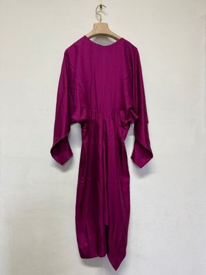 une robe violette suspendue à un cintre devant un mur blanc