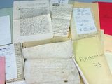 une pile de vieux papiers posée sur une table, sur lesquels on a écrit quelque chose