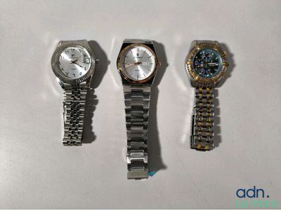 trois montres sont posées les unes à côté des autres sur une surface blanche