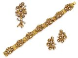 une photo d'un ensemble composé d'un bracelet et d'une boucle d'oreille en or, sertis de perles