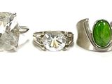 six different rings with green and yellow stones in them on a white surface