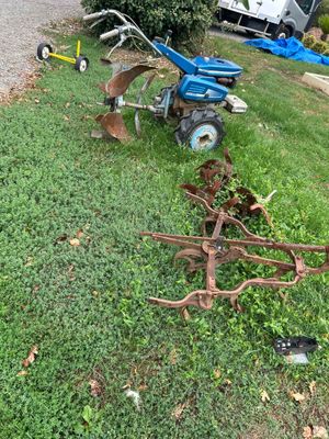 a blue tractor and a plow in the grass