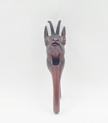 sculpture représentant une tête de chèvre fixée sur un bâton en bois, sur fond blanc