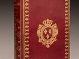 un livre rouge et doré orné d'un emblème doré