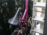 un vélo rose garé près d'une clôture