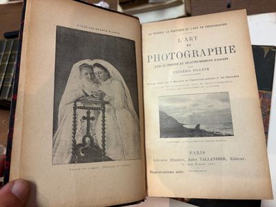 Quelqu'un tient un vieux livre sur lequel figure la photo d'une femme en robe de mariée.