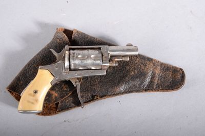 un vieux revolver posé sur un morceau de cuir, sur une surface blanche