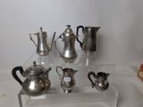 a lot of silver teapots and coffee pots on a table