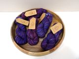 purple and blue yarn in a wooden bowl on a white surface