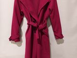 a red coat is hanging on a hanger on a white wall