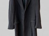 a black coat hanging on a hanger on a white wall