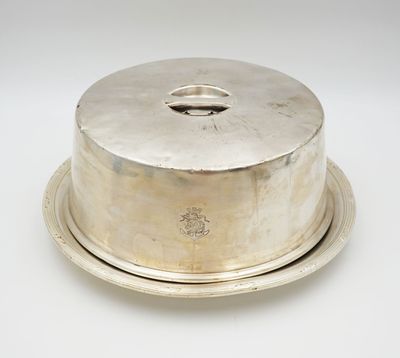 un plat ancien en argent avec un couvercle bombé, posé sur un plateau blanc