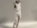 statue d'un homme tenant une raquette de tennis, posée sur une surface blanche