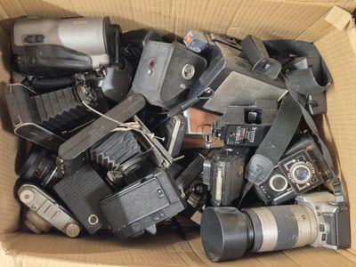 une boîte en carton remplie de vieux appareils photo et d'appareils photo