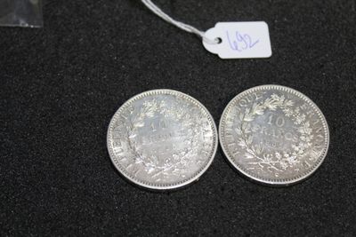 two silver coins sitting next to each other on a black surface