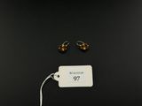 a pair of gold earrings on a black background with a price tag
