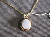 a close up of a gold necklace with a white stone on it