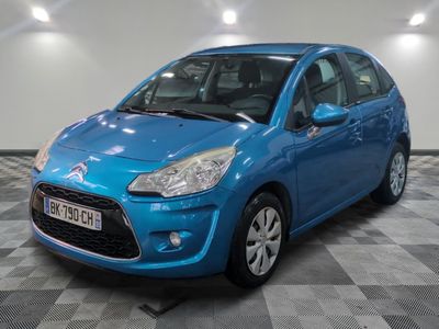 une voiture bleue est garée dans une pièce au sol à carreaux