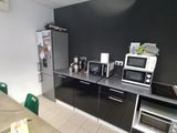 an image of a kitchen with black cabinets and white tile flooring