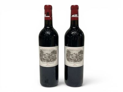 two bottles of red wine sitting next to each other on a white surface