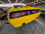 the rear end of a yellow car is parked in a garage