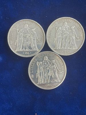 three silver coins sitting on top of a blue cloth
