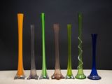 Plusieurs vases en verre de différentes couleurs sont alignés sur une table