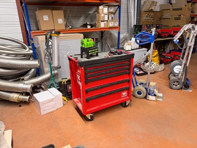 a red tool cart in a garage with a lot of tools on it