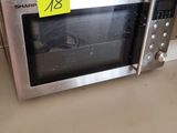 a microwave sitting on a counter with a yellow sticker on it