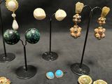 several pairs of earrings are displayed on a stand on a black background