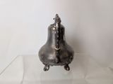 a silver bell sitting on a glass shelf in front of a white wall